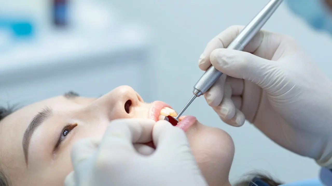 Zubní lékař měří hloubku dásňových kapes sondu při klinickém vyšetření.